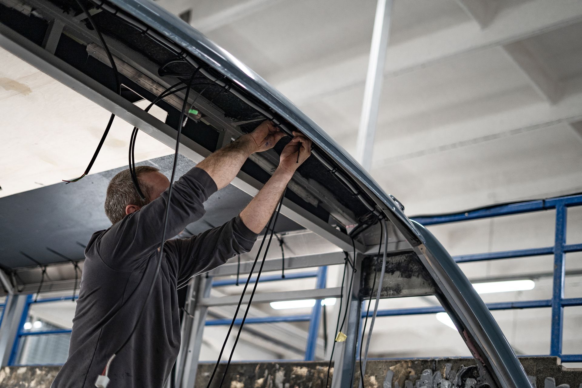 Technician wiring the interior frame of a vehicle in a workshop