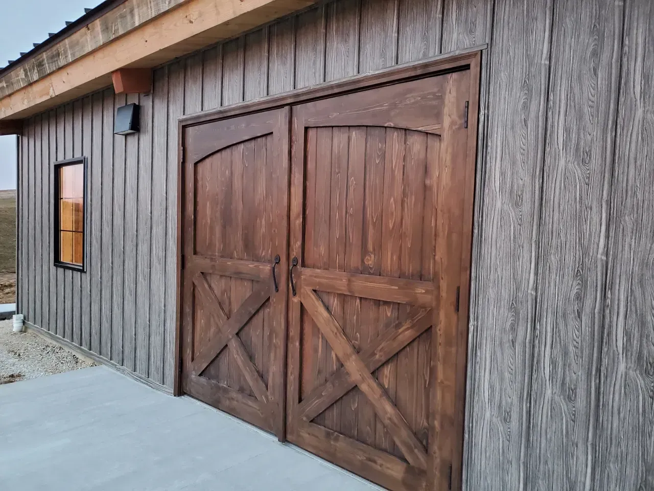 A wooden garage door with a window on the side of a building.