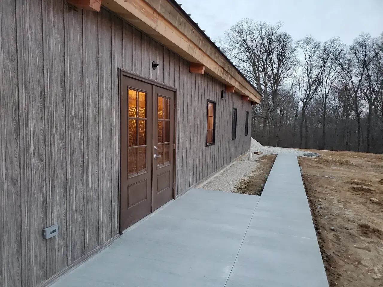 A large wooden building with a concrete walkway leading to it.