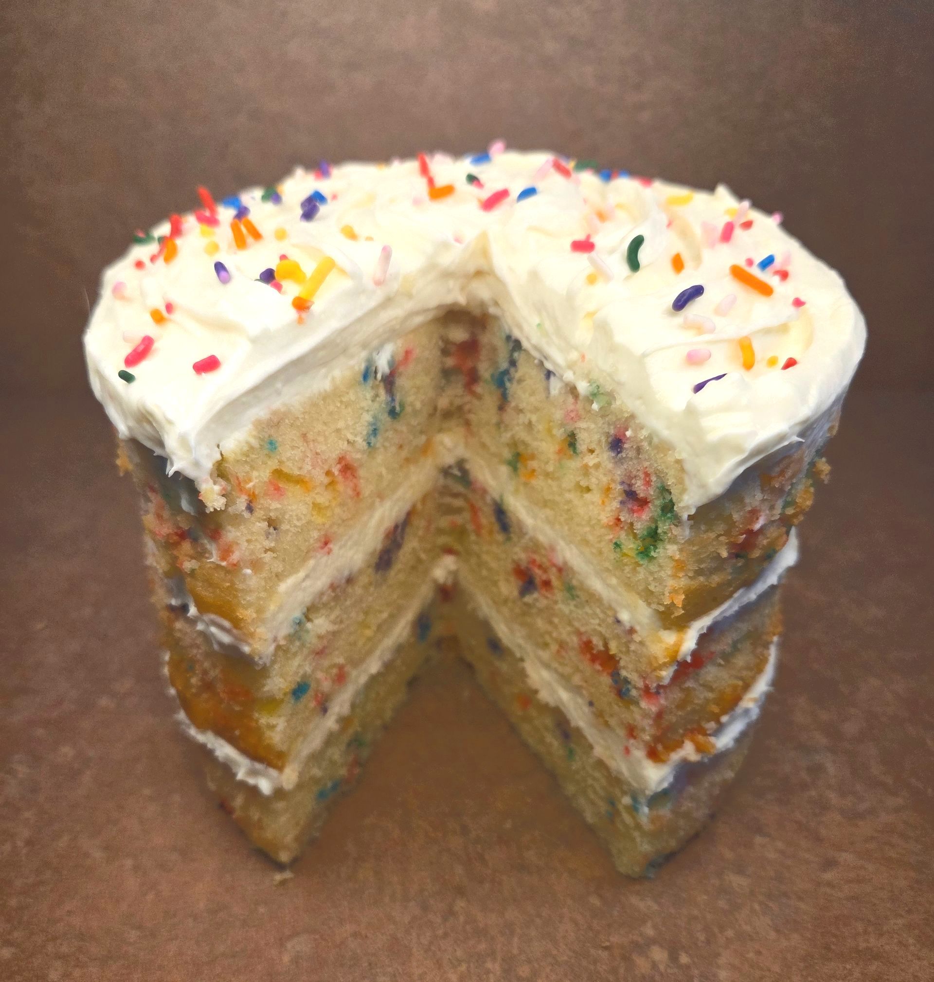 Overhead view of a birthday flavored cake with a slice taken out
