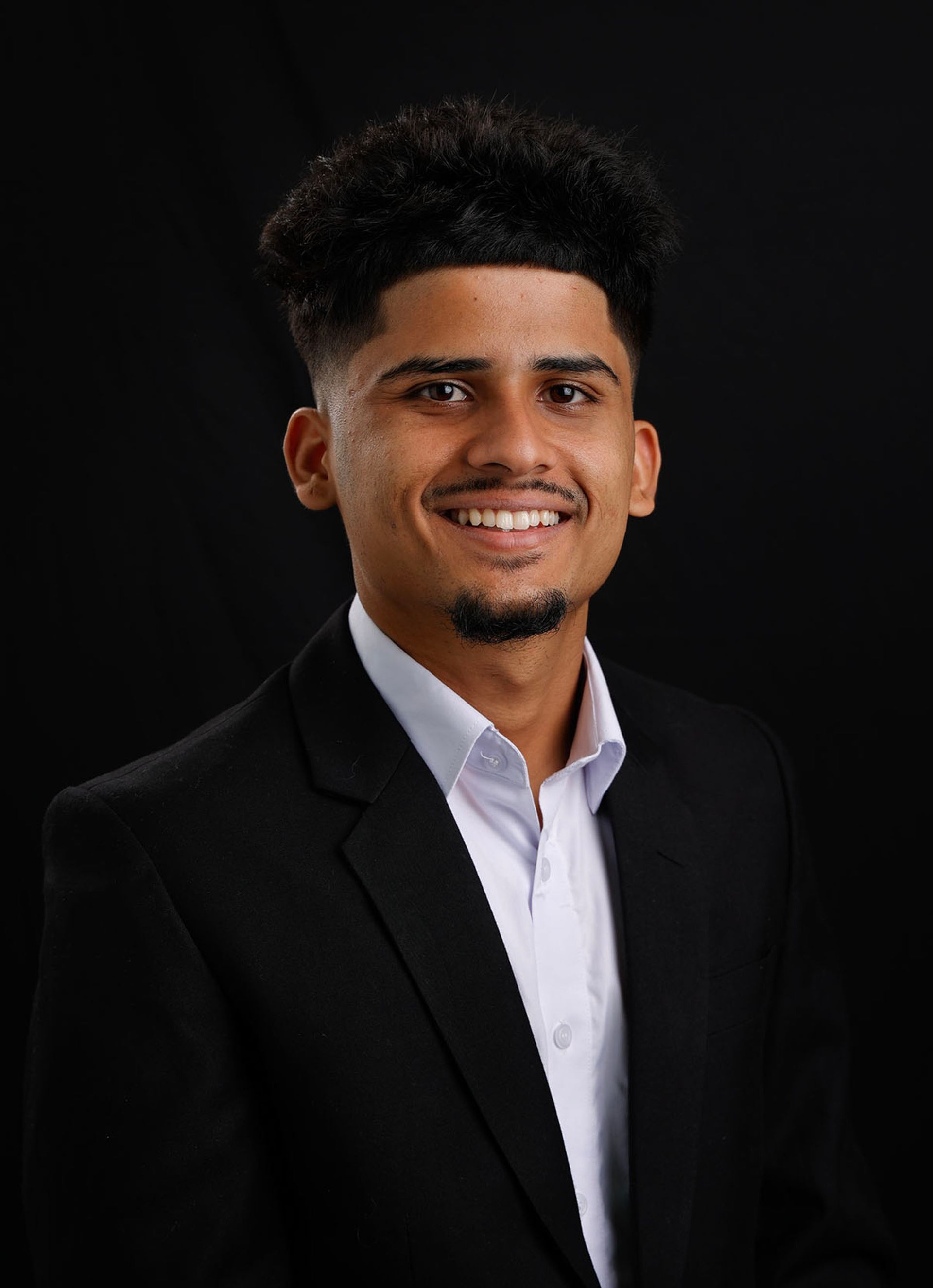 A man in a suit and blue shirt smiles for the camera