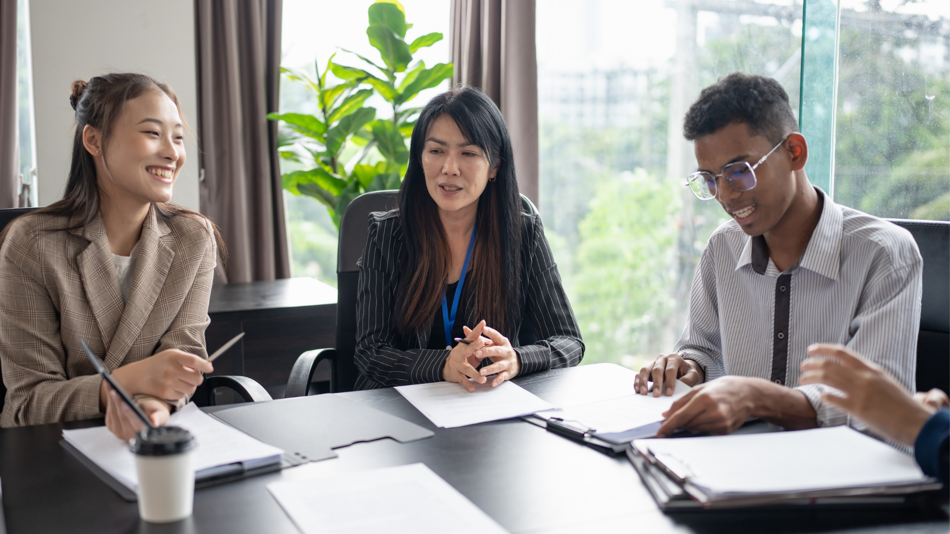 Business meeting with people discussing around a table, hands gesturing over documents and a calculator.