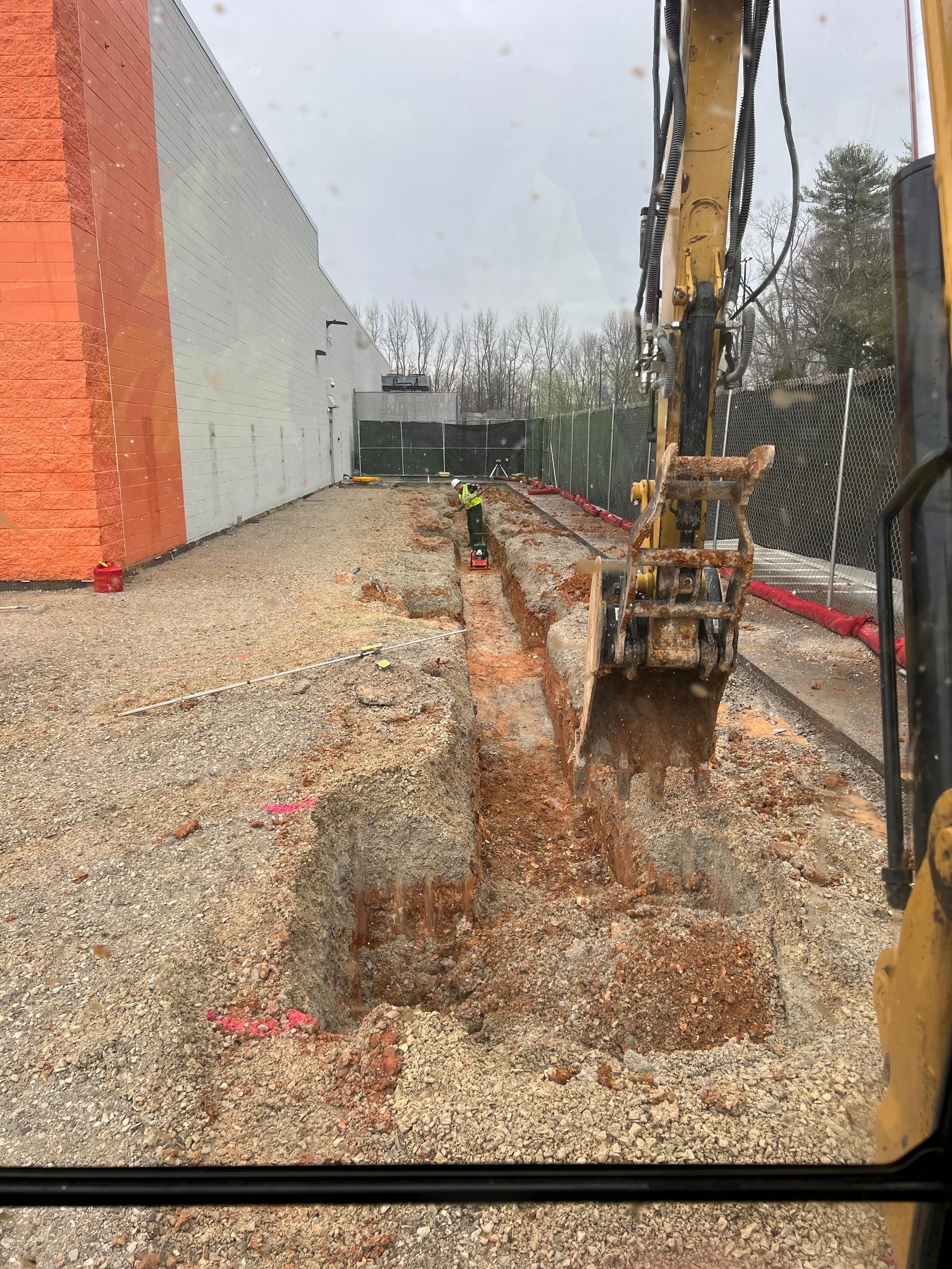 A bulldozer is digging a hole in the ground in front of a building.