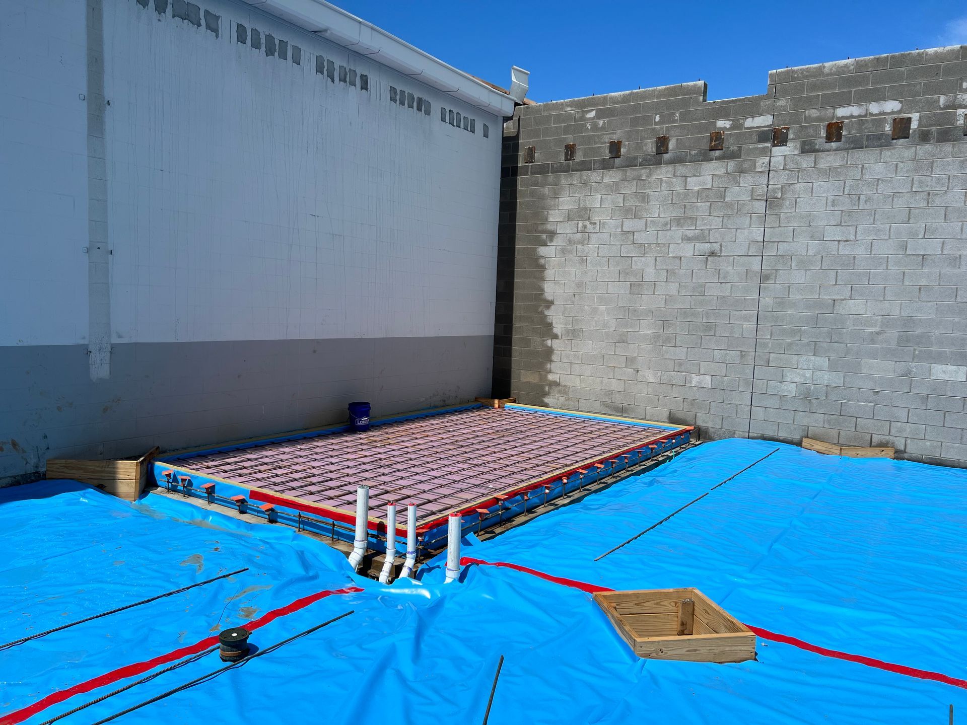 A building under construction with a blue tarp on the ground.