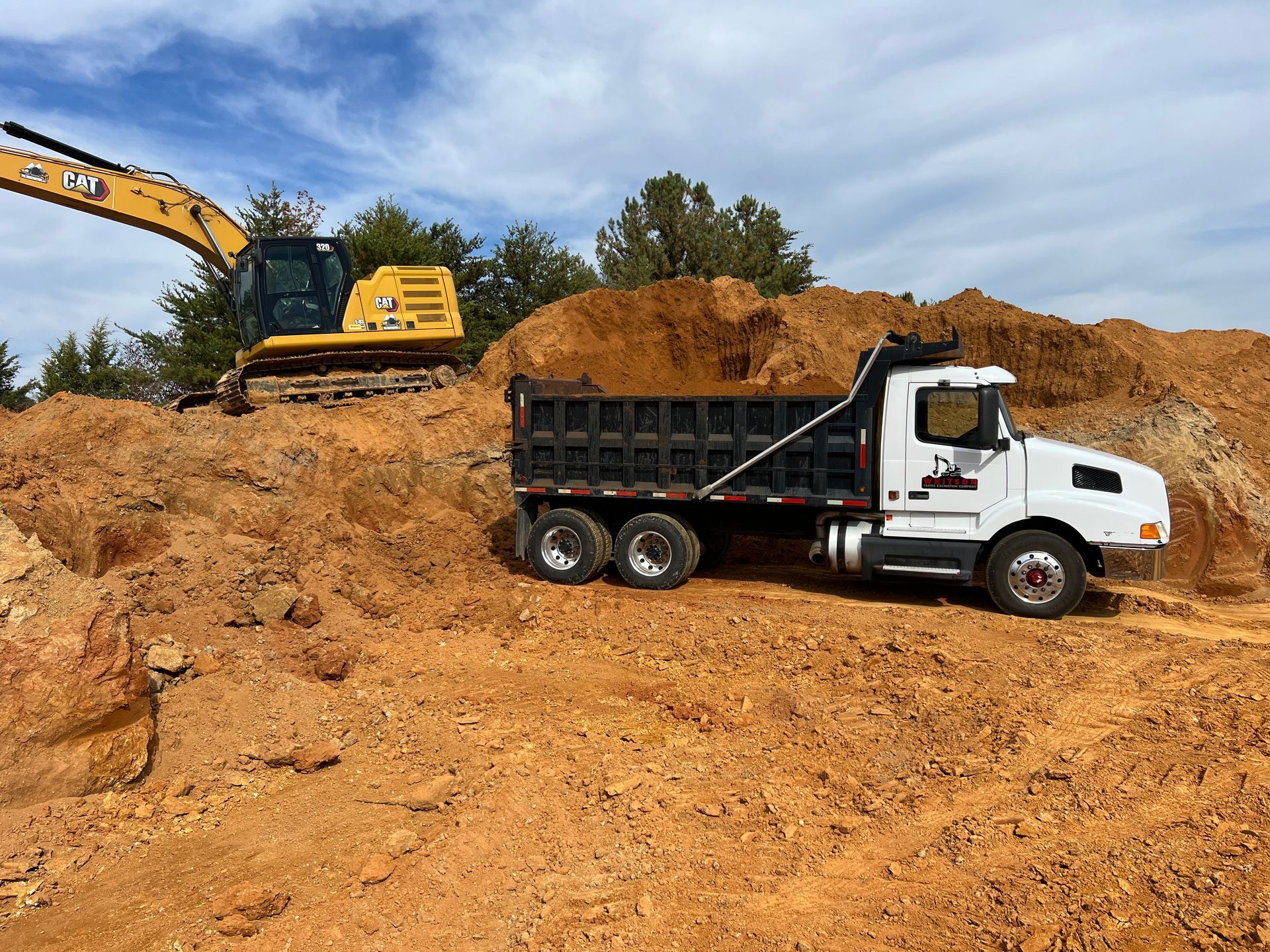 A dump truck is parked in front of a pile of dirt.