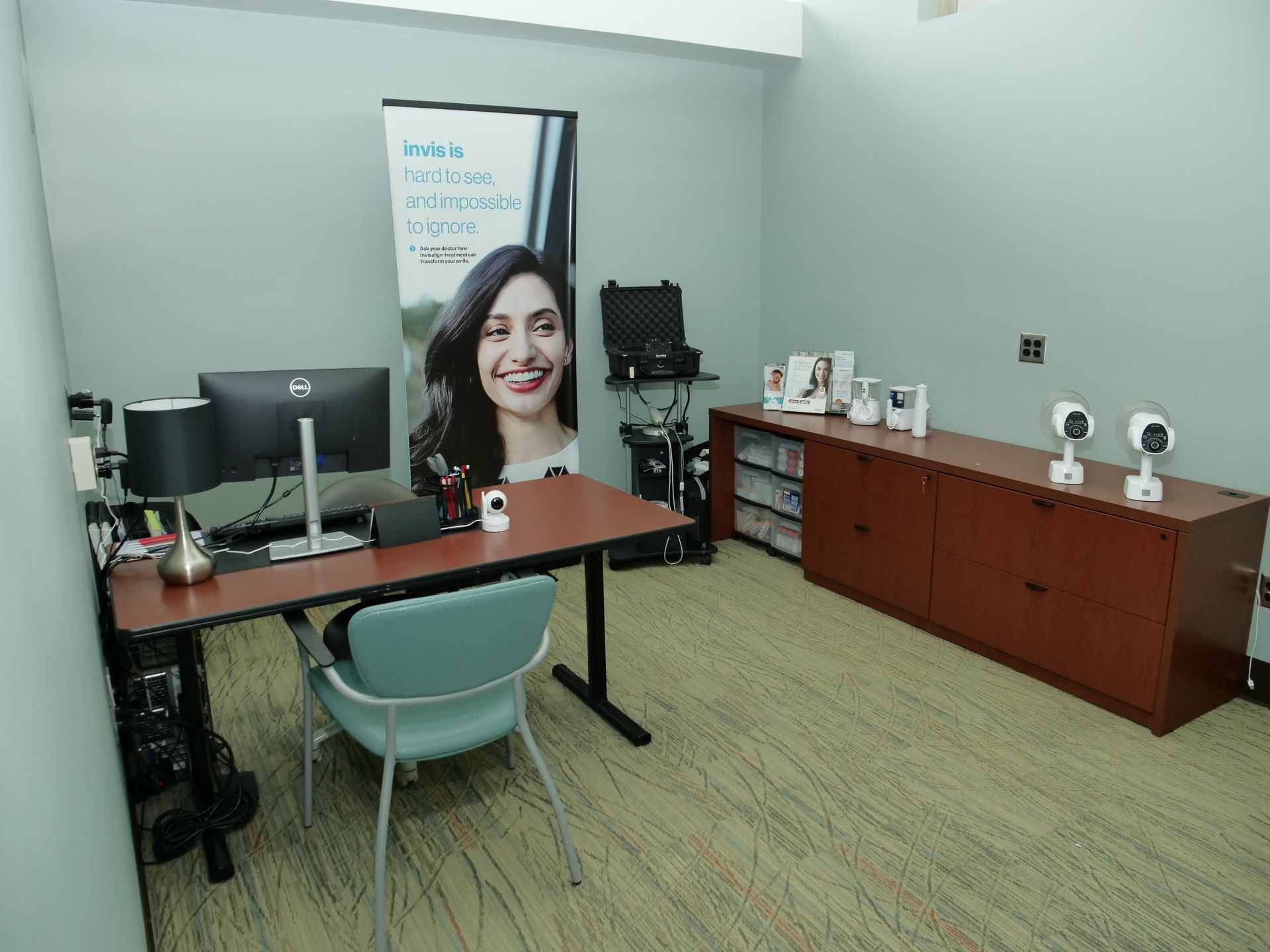 Office with desks, computer monitors, printer, and a large portrait poster on the wall.