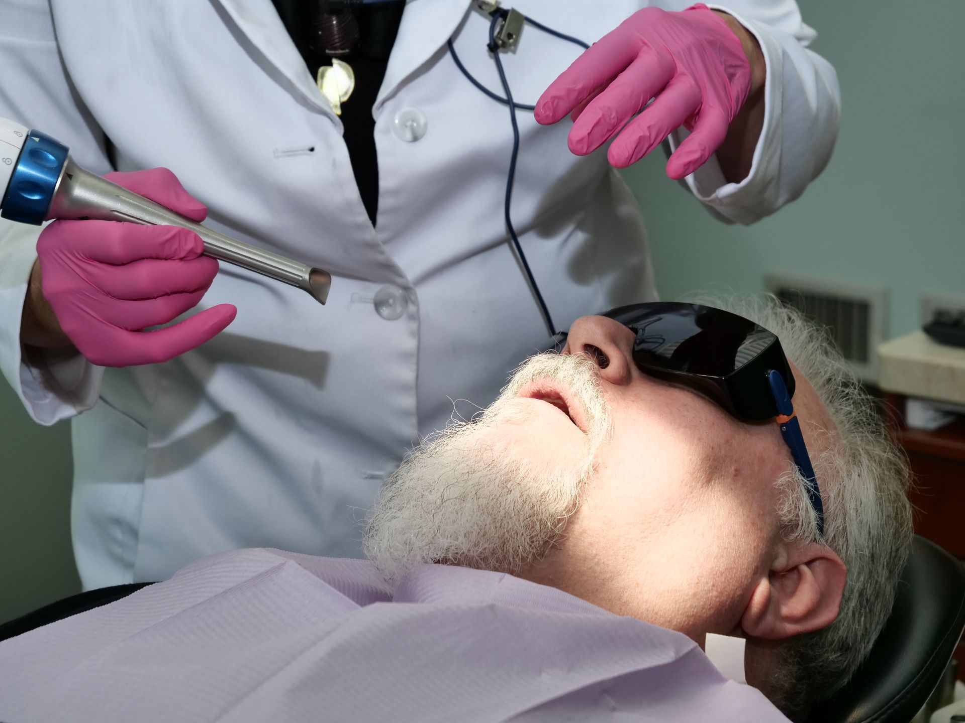 Dentist using a drill on a patient wearing safety glasses in a dental chair