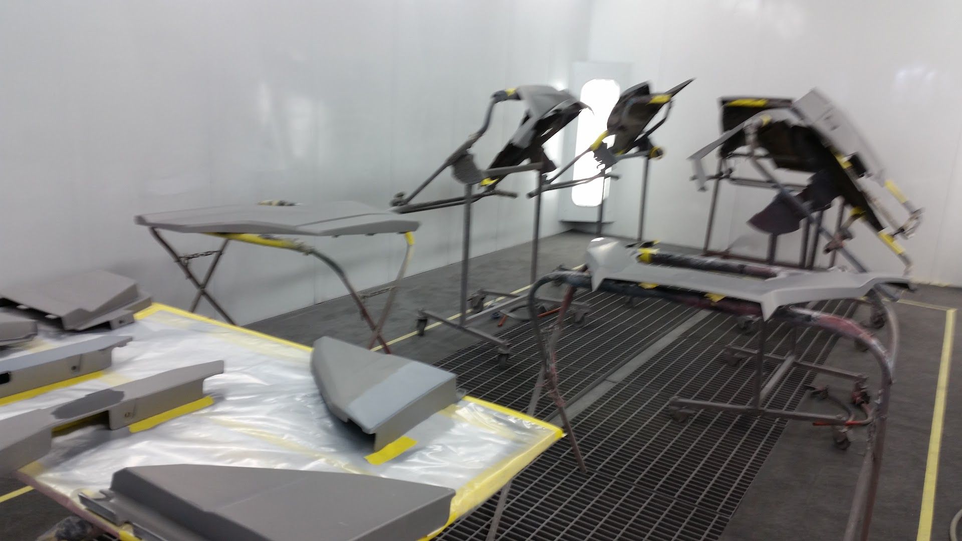 Workshop with a large table of metal frames, tools, and materials arranged under bright lights | Autotech Service
