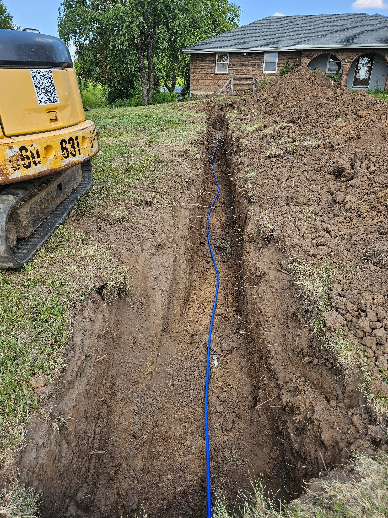 A bulldozer is digging a hole in the dirt in front of a house.