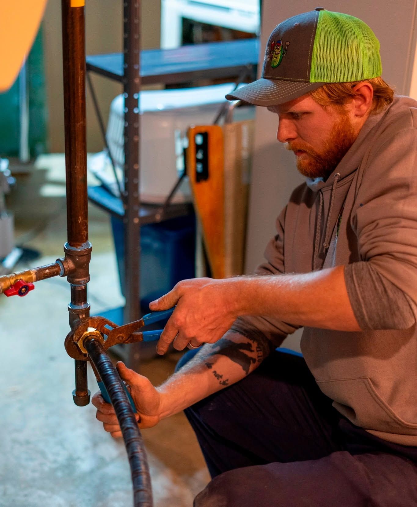 A man wearing a green hat is working on a pipe