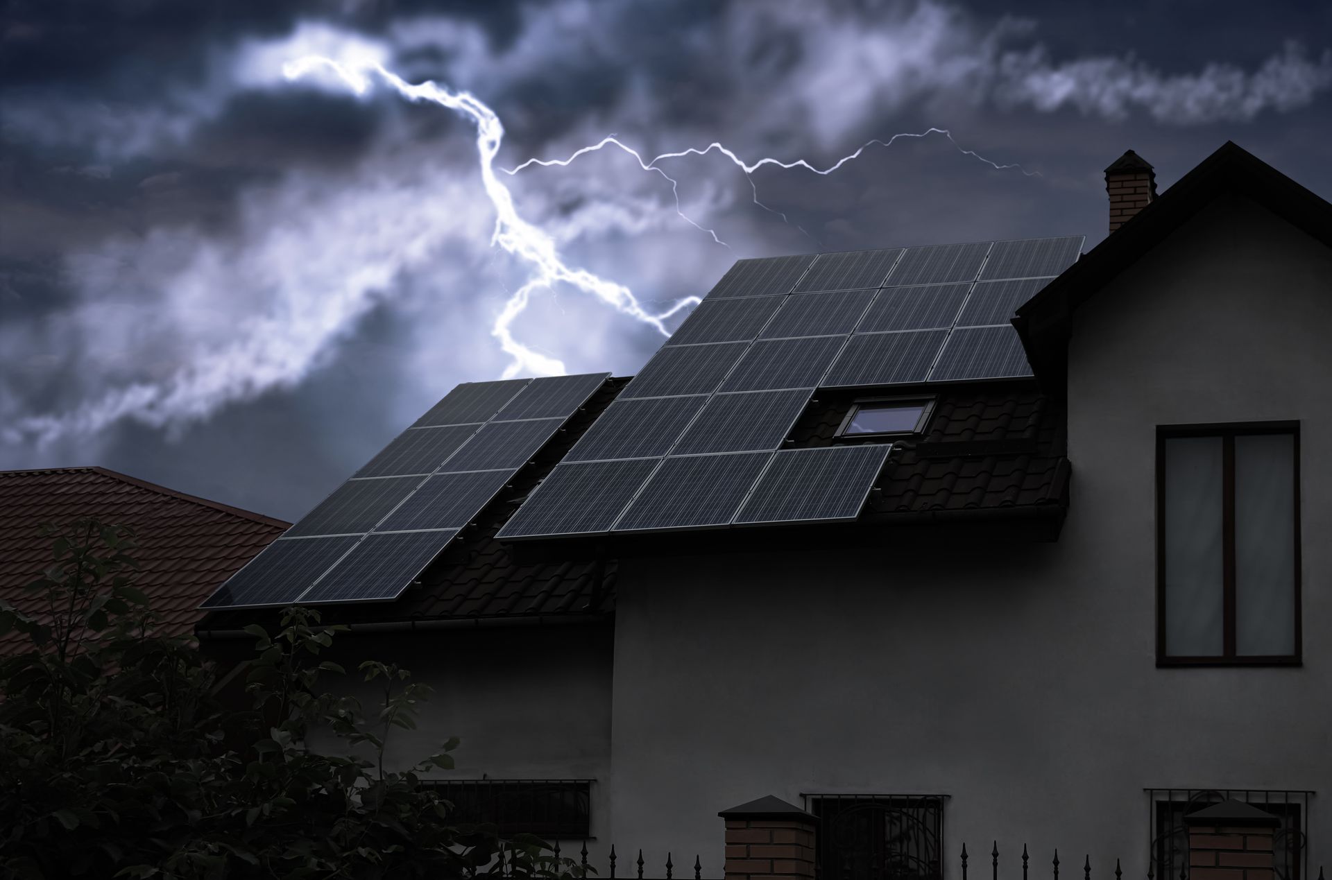 Lightning striking a house with solar panels on the roof under a stormy sky.