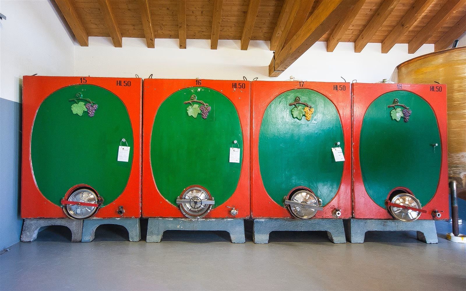 In un locale industriale, quattro grandi serbatoi arancioni e verdi erano allineati sotto un tetto di legno.