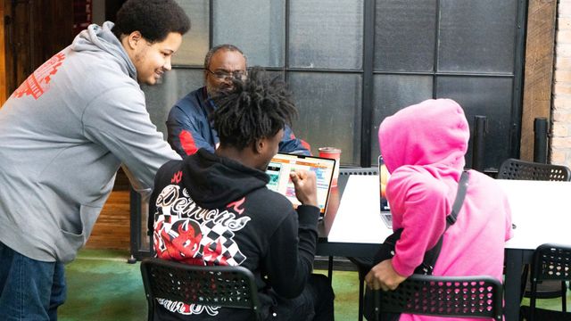 CODE313 instructor helping students at a school
