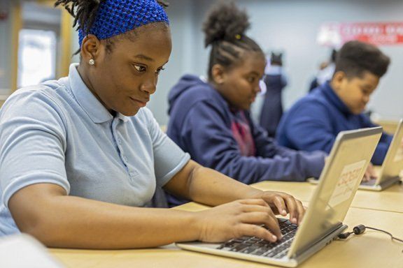Scholars collaborating on laptops in a CODE313 class