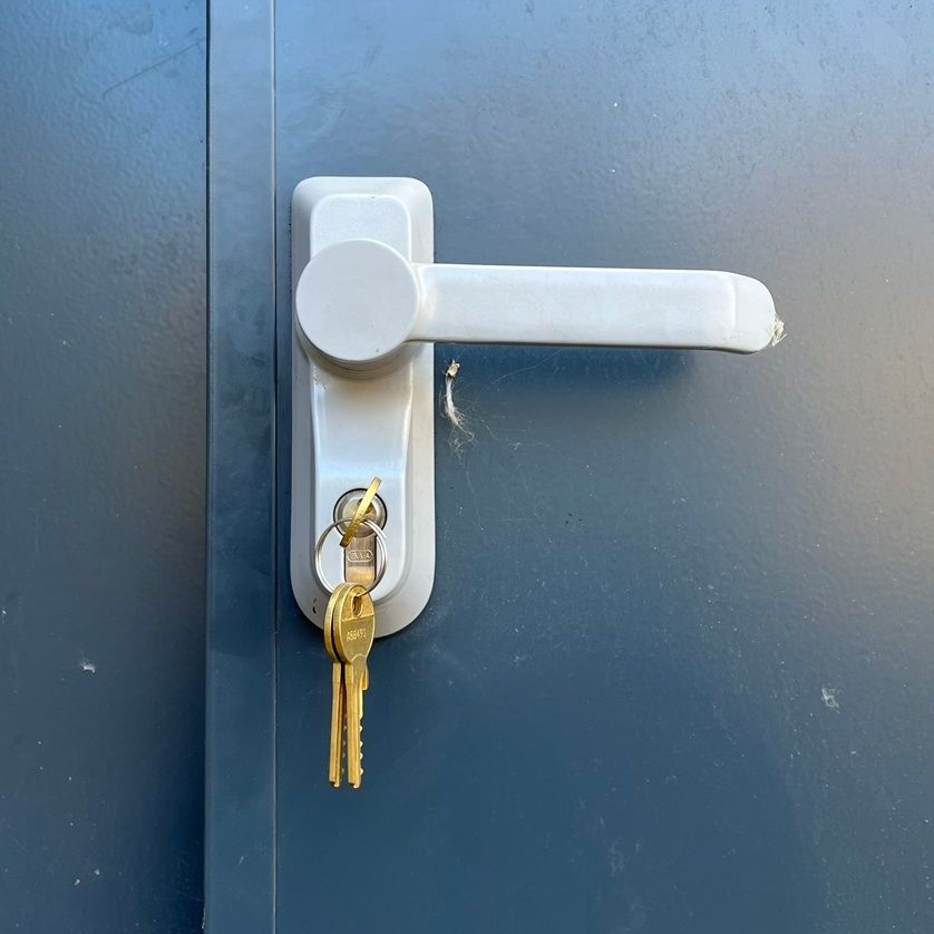 Gray door handle with keys in the lock on a dark blue door.