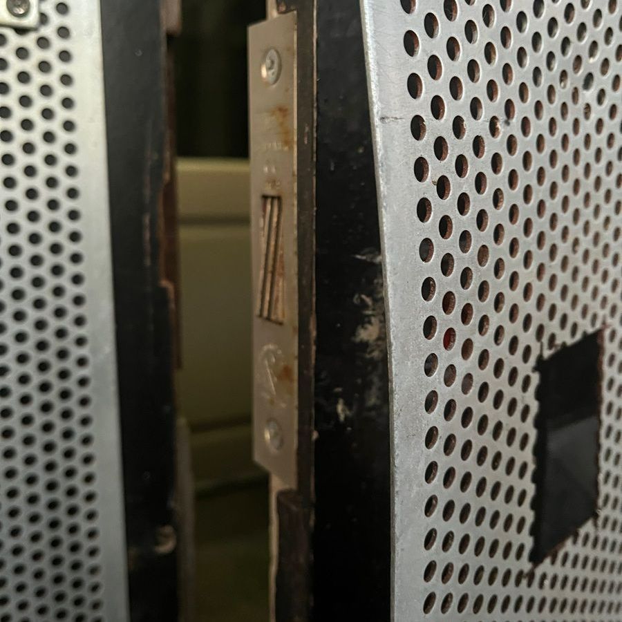 Metal door with a silver lock and perforated design.