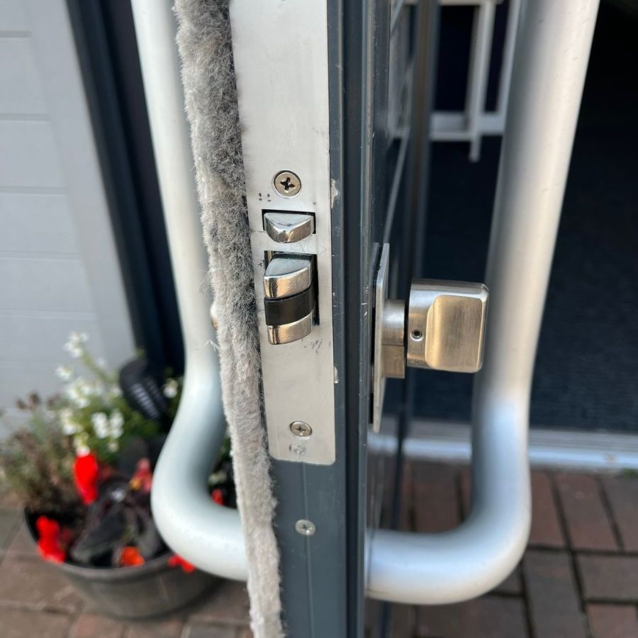 Close-up of a door lock with a handle. Ajar, showing lock components. Gray door and hardware.