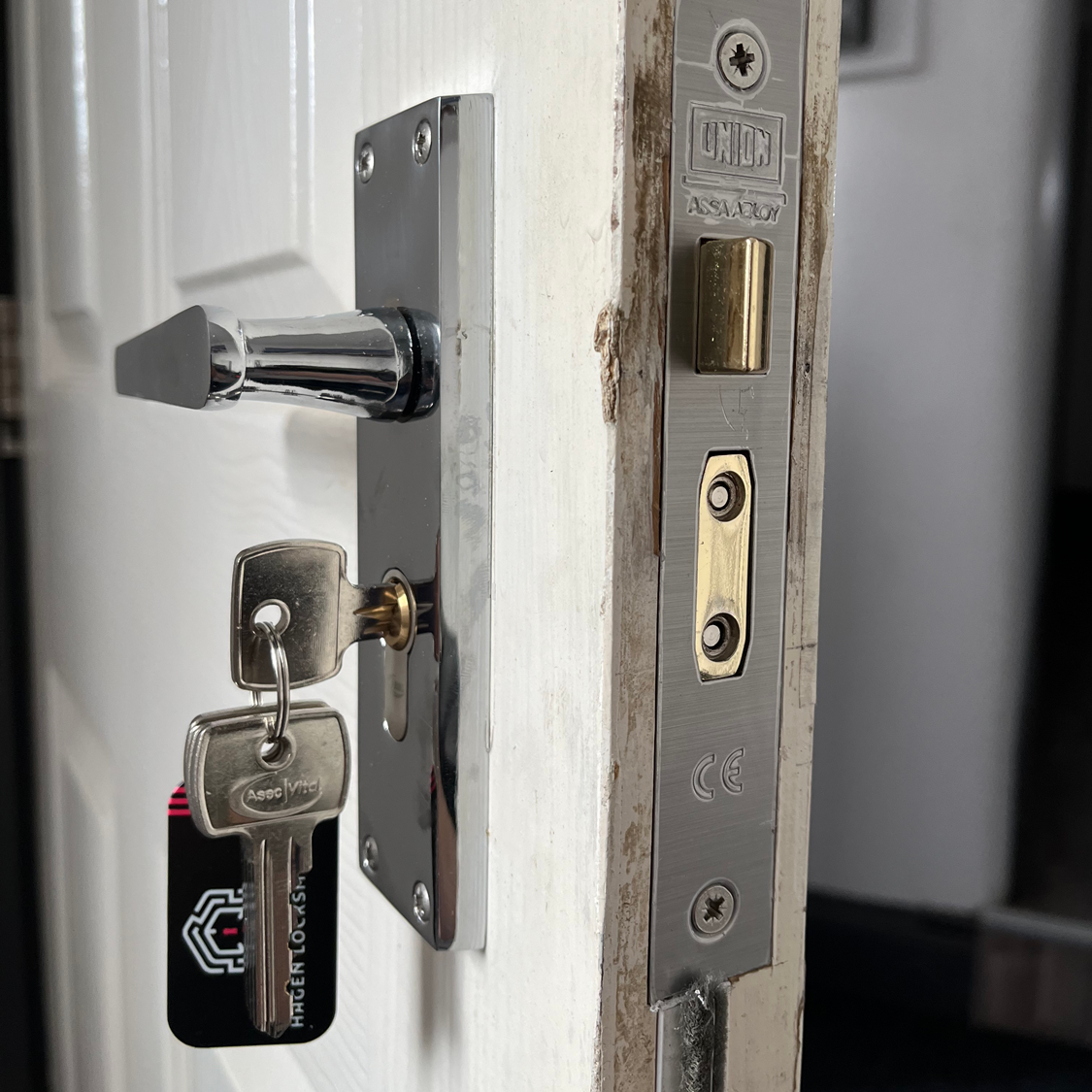 Door with chrome lever handle, key in lock, and latch plate on the door frame.