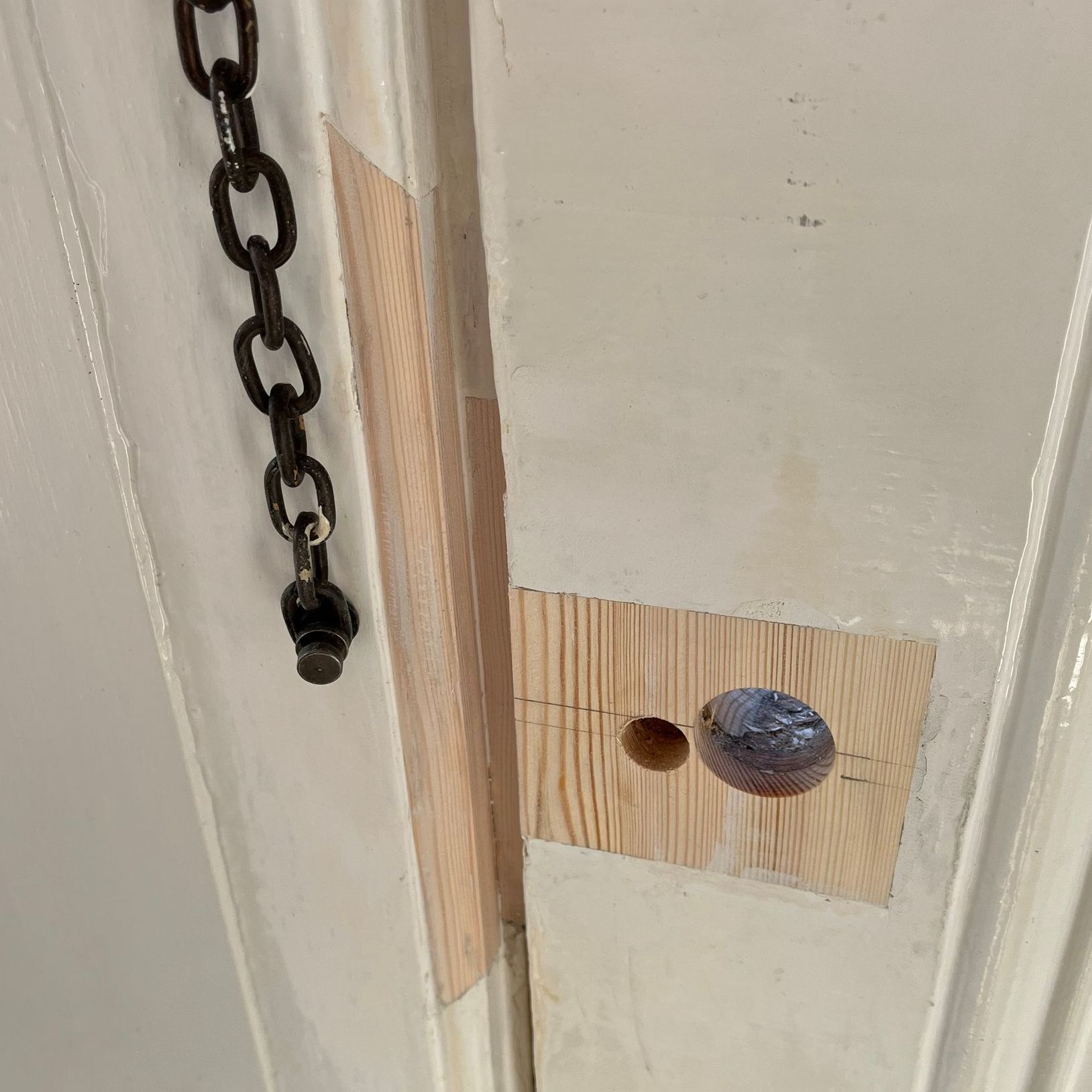White door with wooden patch and chain.