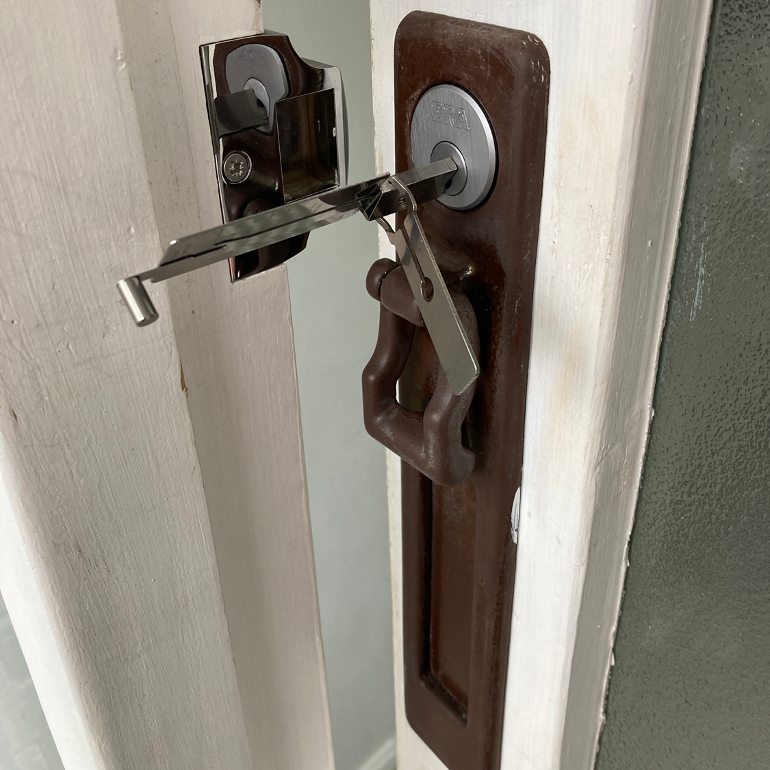 A door with keys and lock picks in the keyhole, brown handle, white frame.