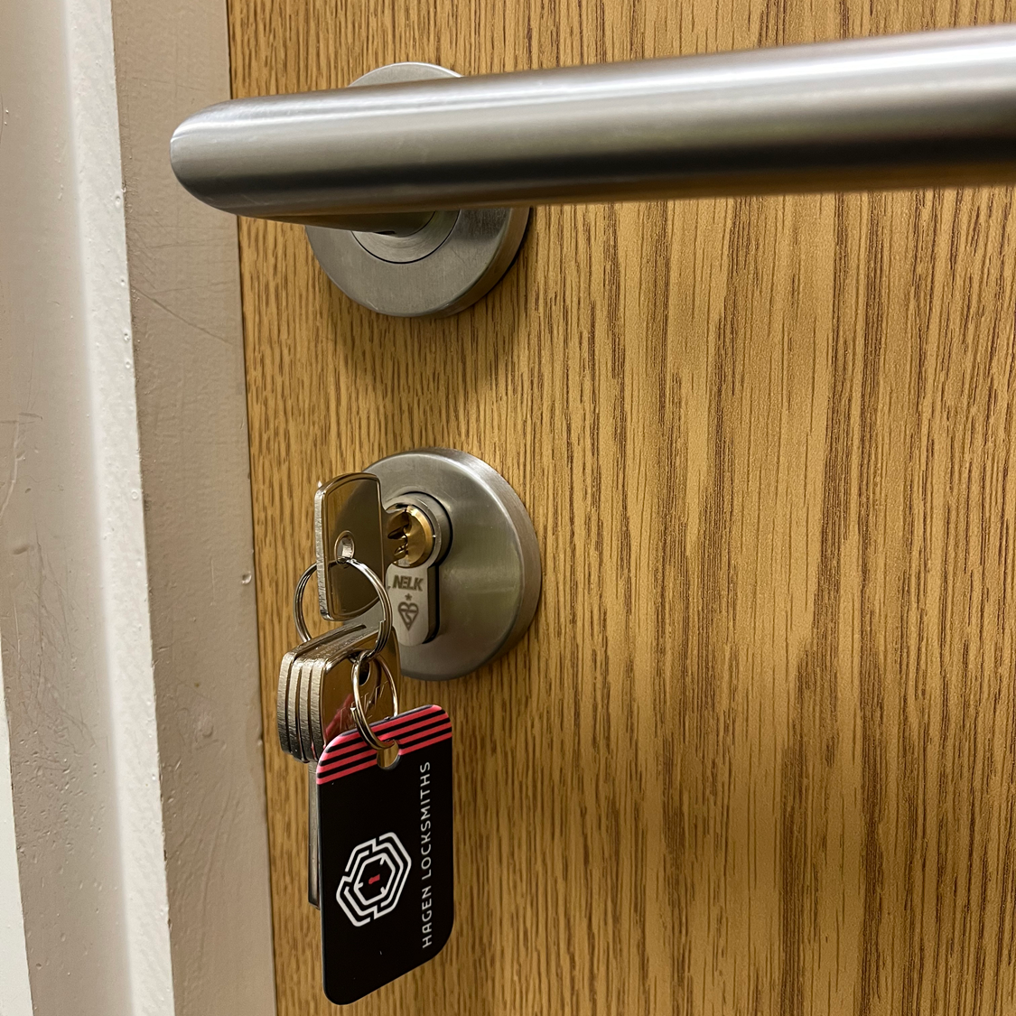 Door with silver handle and lock; keys inserted. Red key tag visible.
