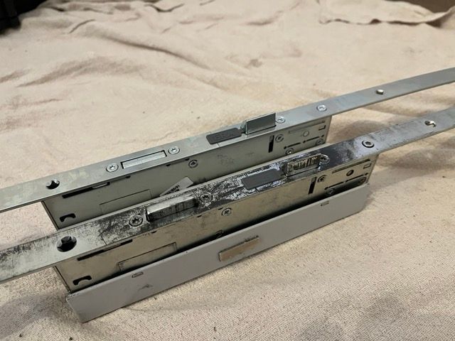 Three metal drawer slides stacked on a beige fabric surface