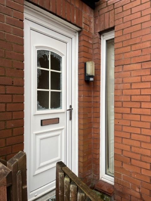 White front door in a red brick house, with a mailbox and a small porch railing.