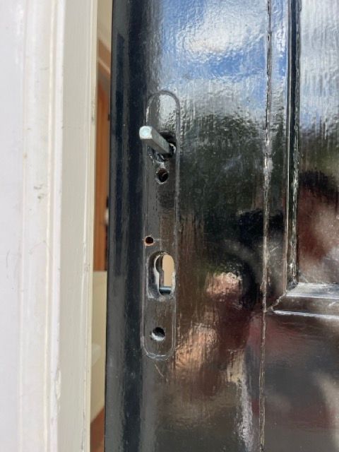 Close-up of a black door lock and handle on a glossy dark door frame