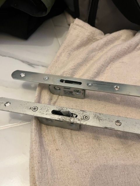 Close-up of two metal furniture brackets on a beige upholstered cushion or blanket.