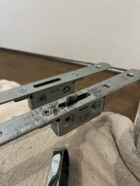 Close-up of two worn metal drawer slides resting on a beige cloth surface.