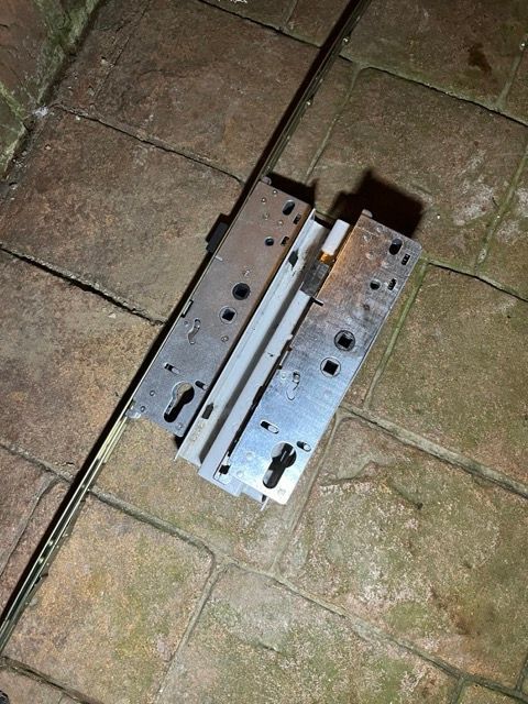 Two metal drawer slide brackets lying on wet stone paving at night