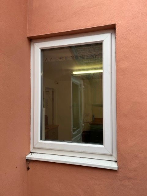 White-framed window in an orange wall, showing a dim interior room.