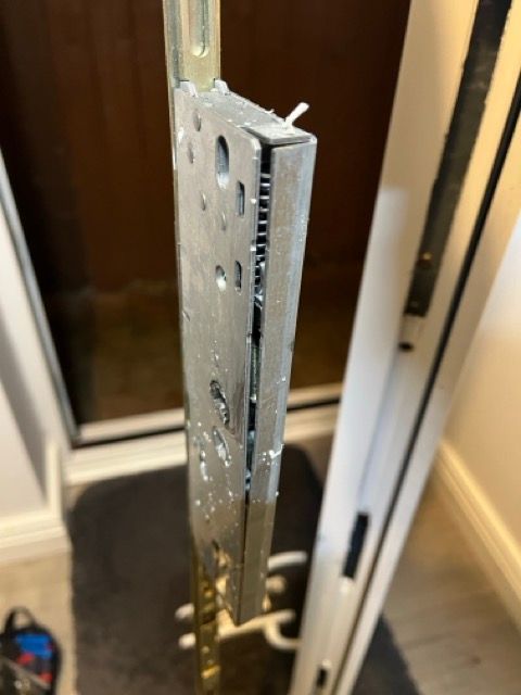 Close-up of a metal sliding door hinge on a white door frame.
