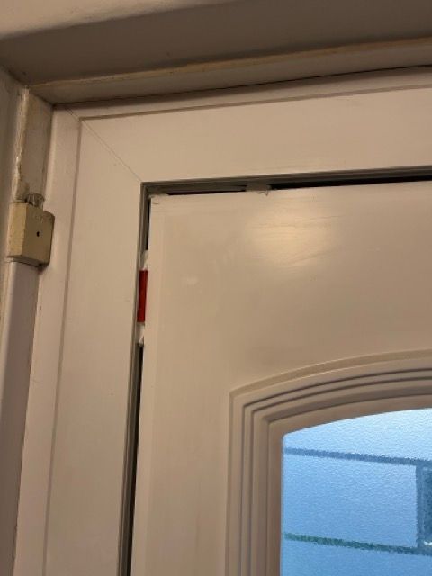Close-up of a white door slightly ajar with visible hinge and frosted blue window panel