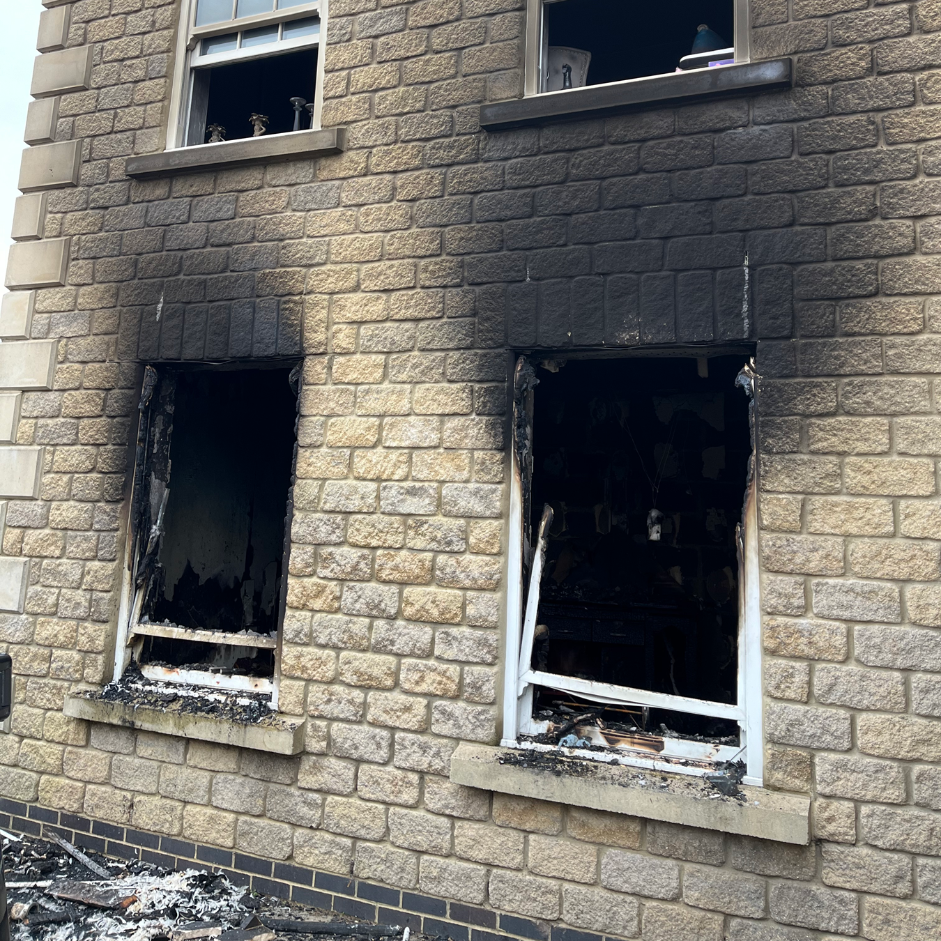 Building facade with two charred windows, smoke damage visible.