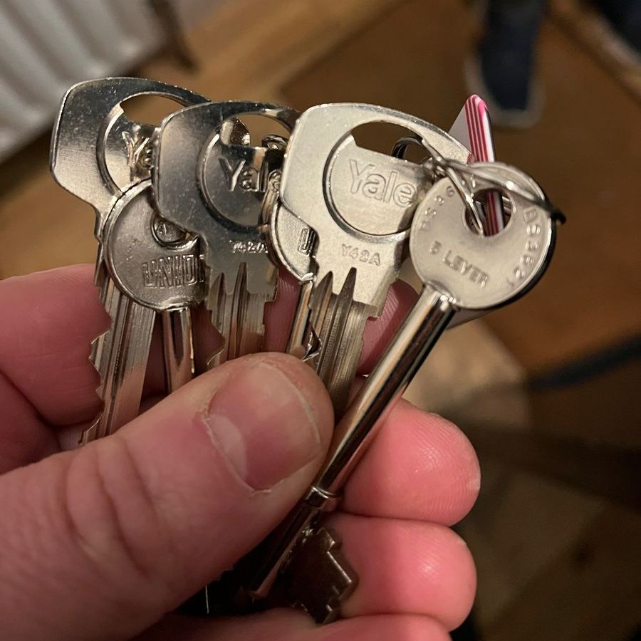 Hand holding a stack of four silver Yale keys.
