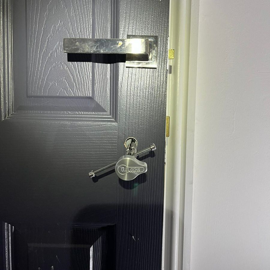 Black door with silver hardware: handle and security key in the lock.