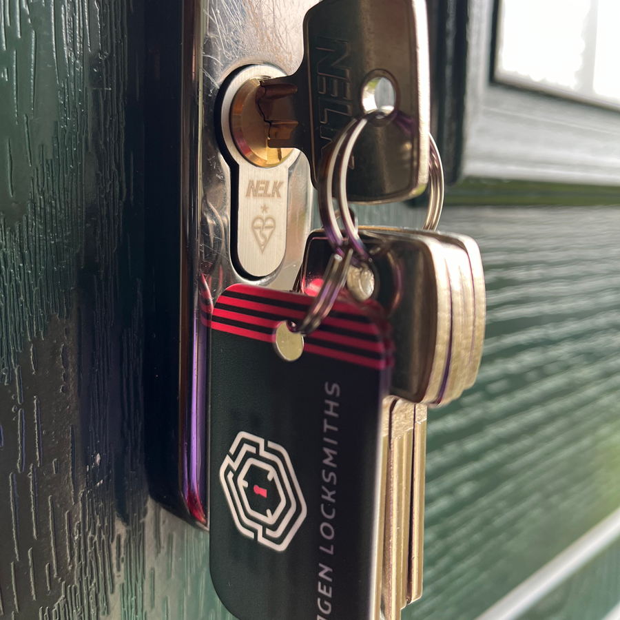 Keys in a door lock, one key inserted. A keychain tag reads