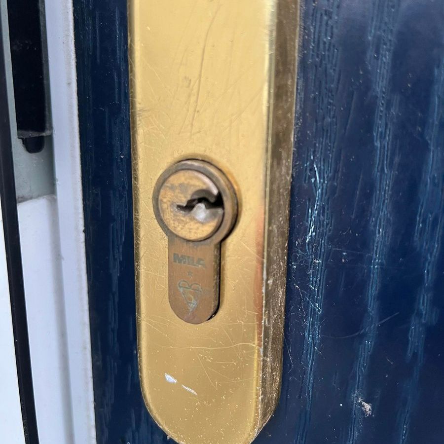 Gold-colored door lock on a blue door. The keyhole has a Yale logo.