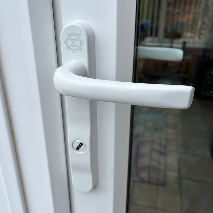 White door handle on a white door. The handle has a key lock and a curved design.