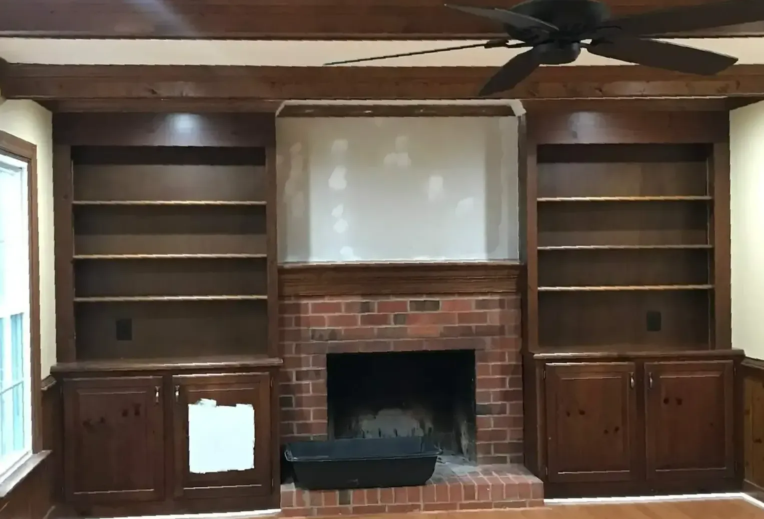 A living room with a fireplace and a ceiling fan