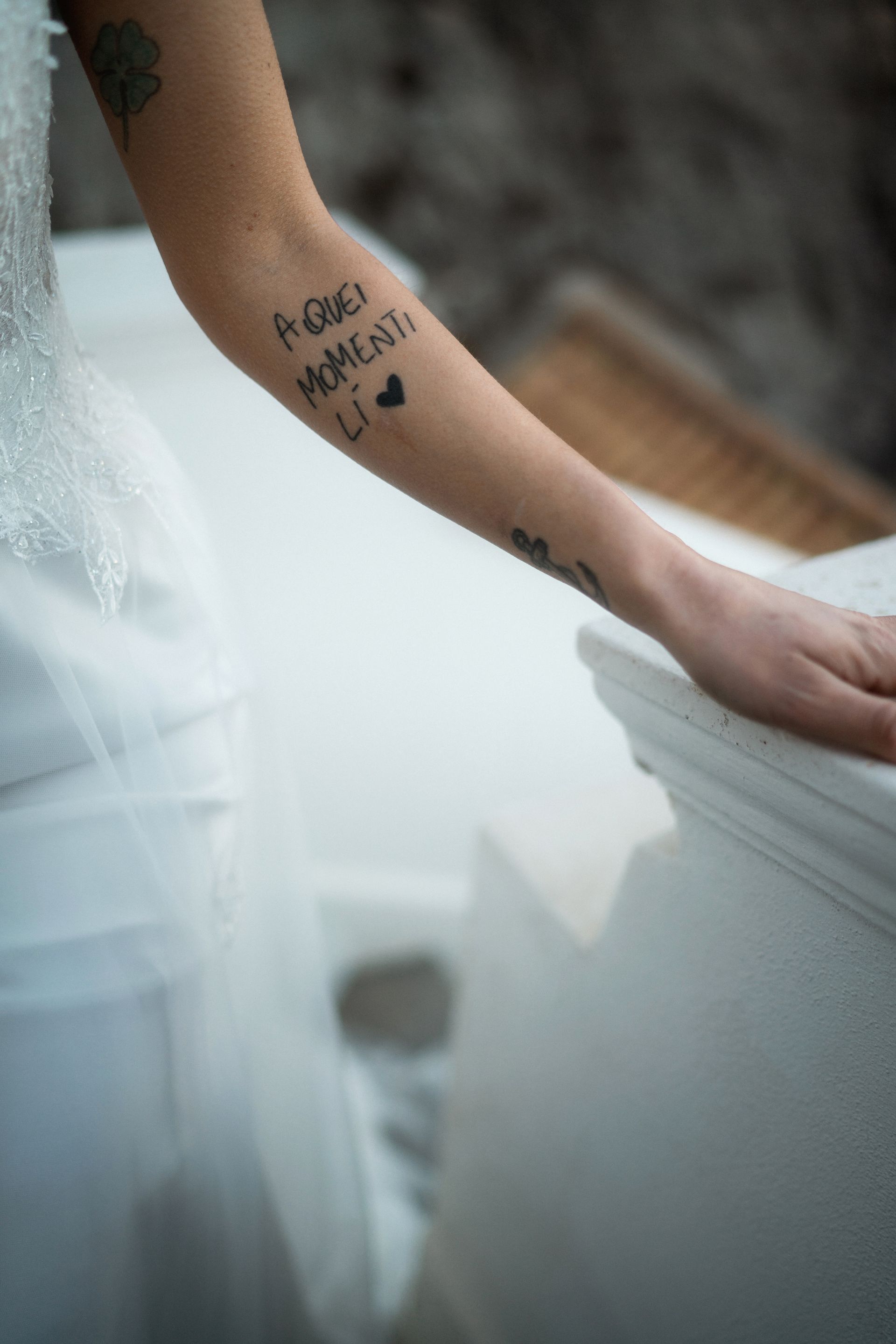 Donna in abito bianco con tatuaggio sul braccio che recita 