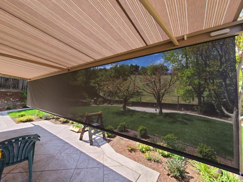 A patio with a screened in awning overlooking a lush green yard.
