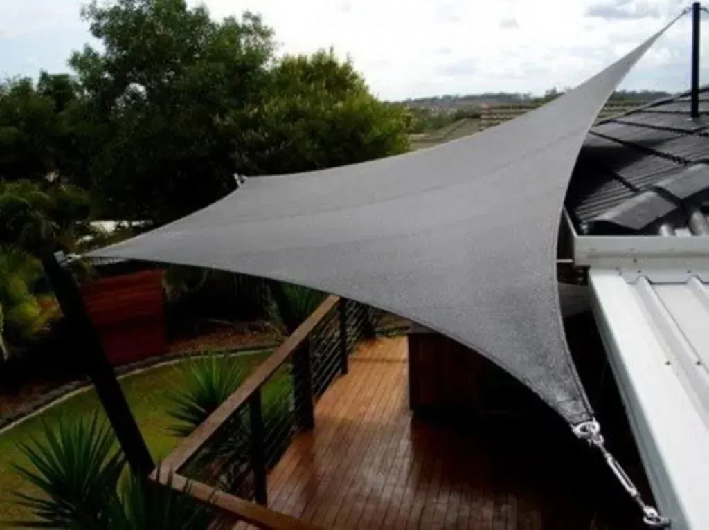 A pergola with a screen on the side of it in a backyard.