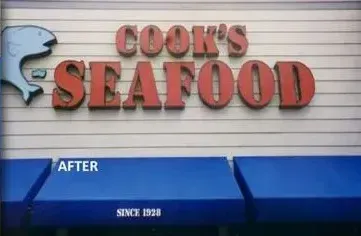 A sign for cook 's seafood with a blue awning