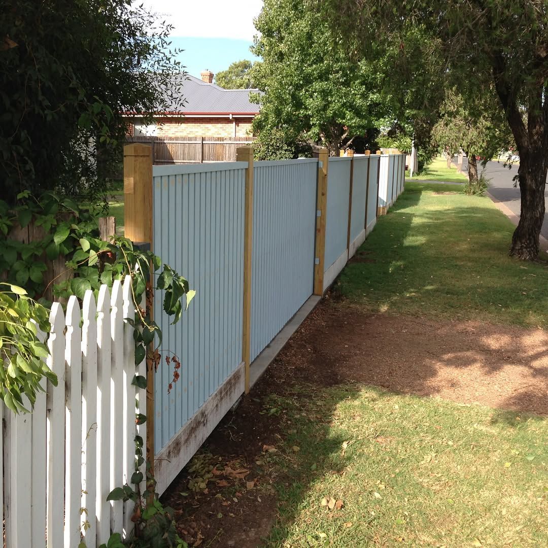 Black metal fence with decorative circles and yellow autumn leaves in the background