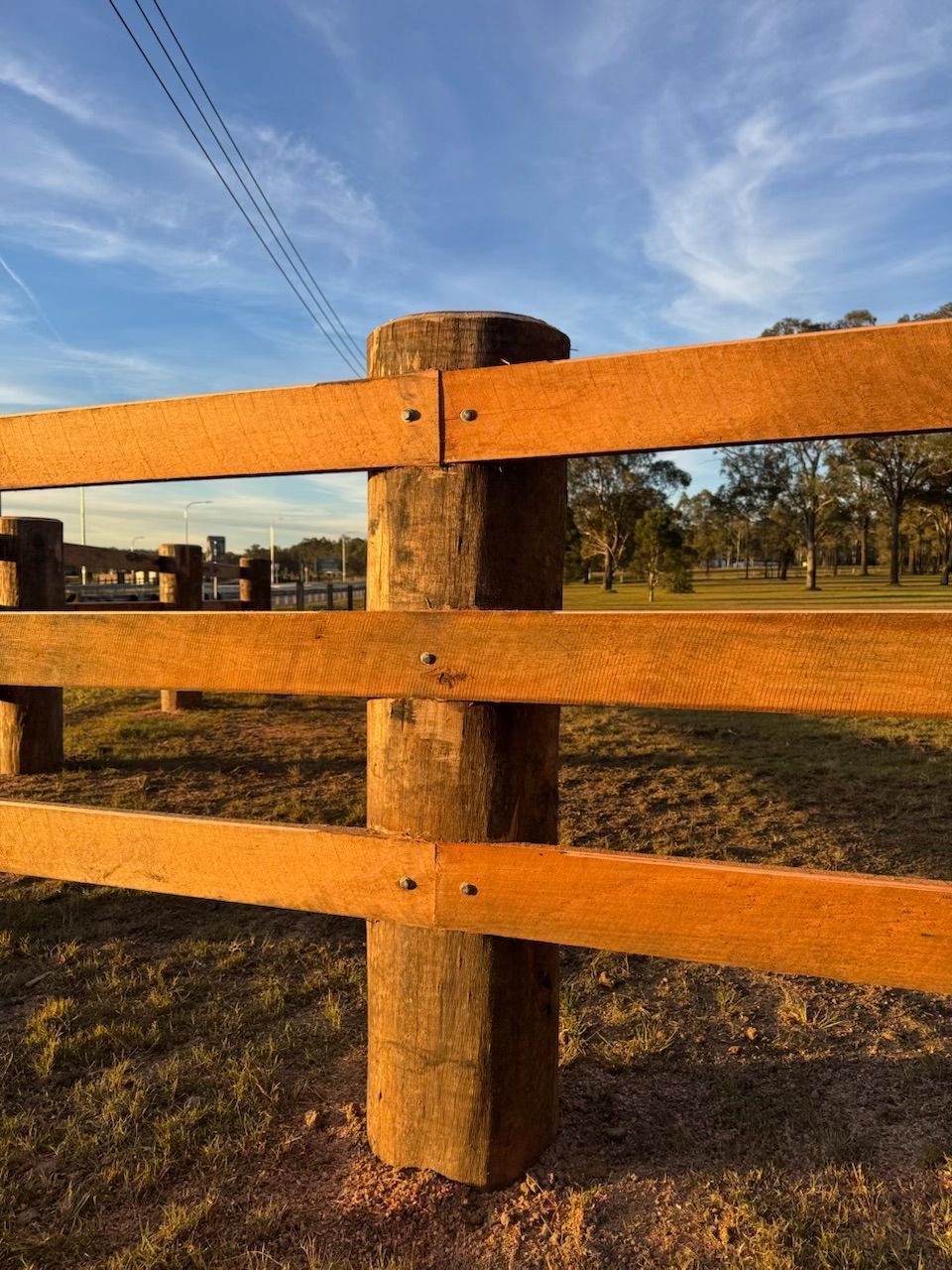 Wooden fence in a sunlit field under a blue sky