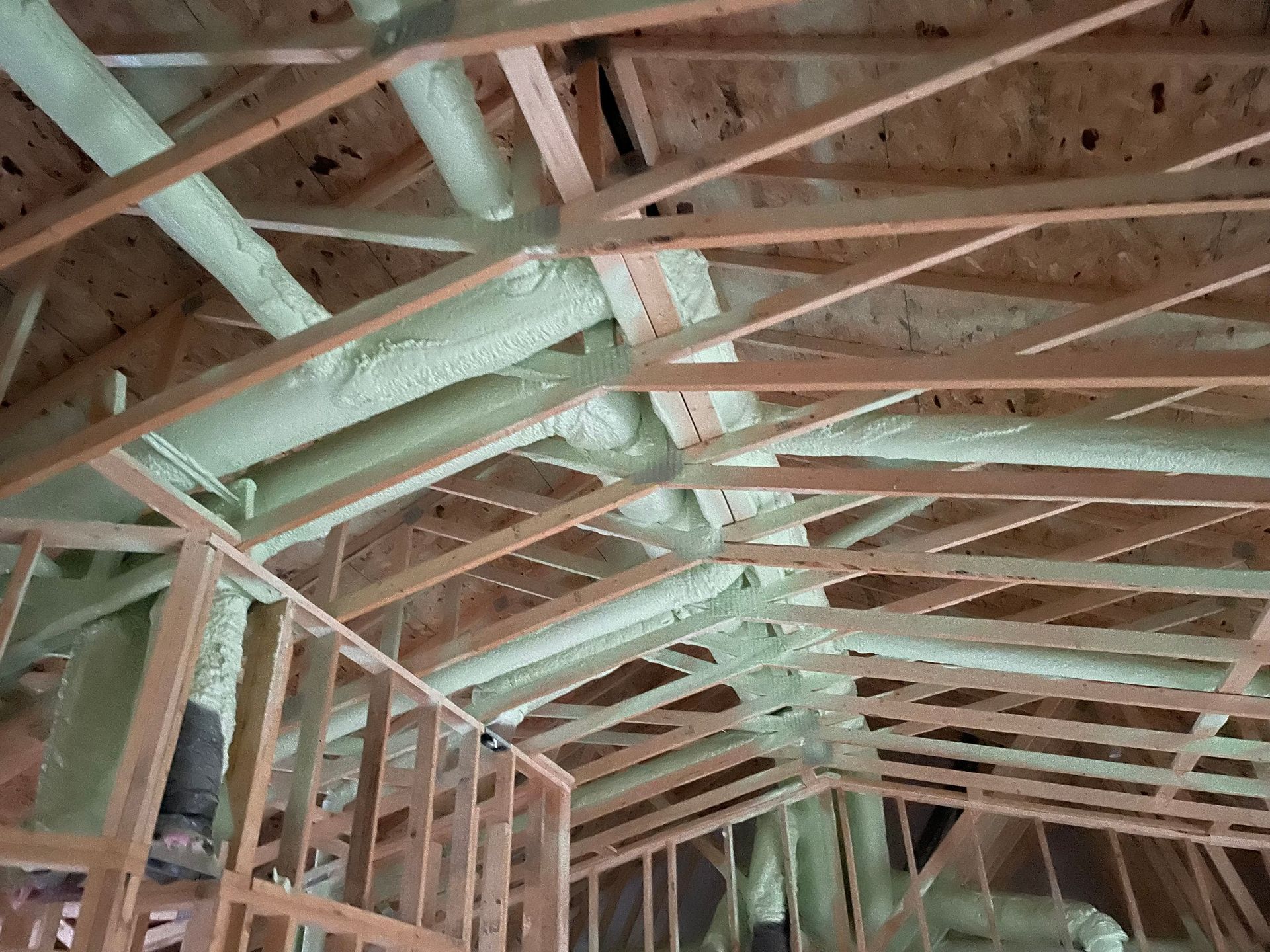 Attic rafters with spray-foam insulation on the underside of a roof