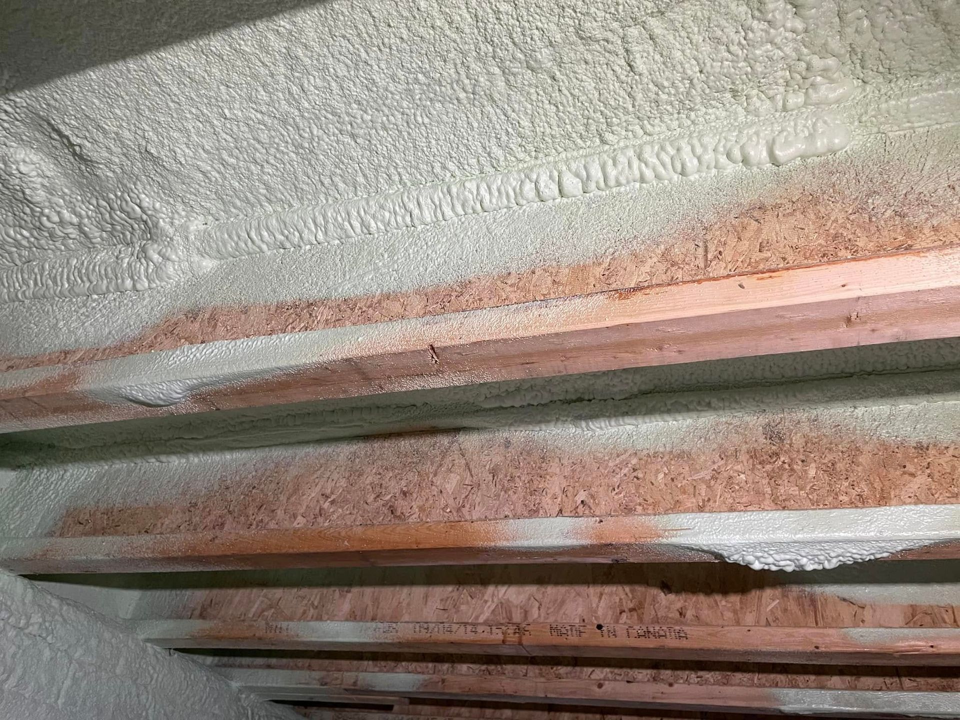Close-up of pink and white textured insulation between wooden beams