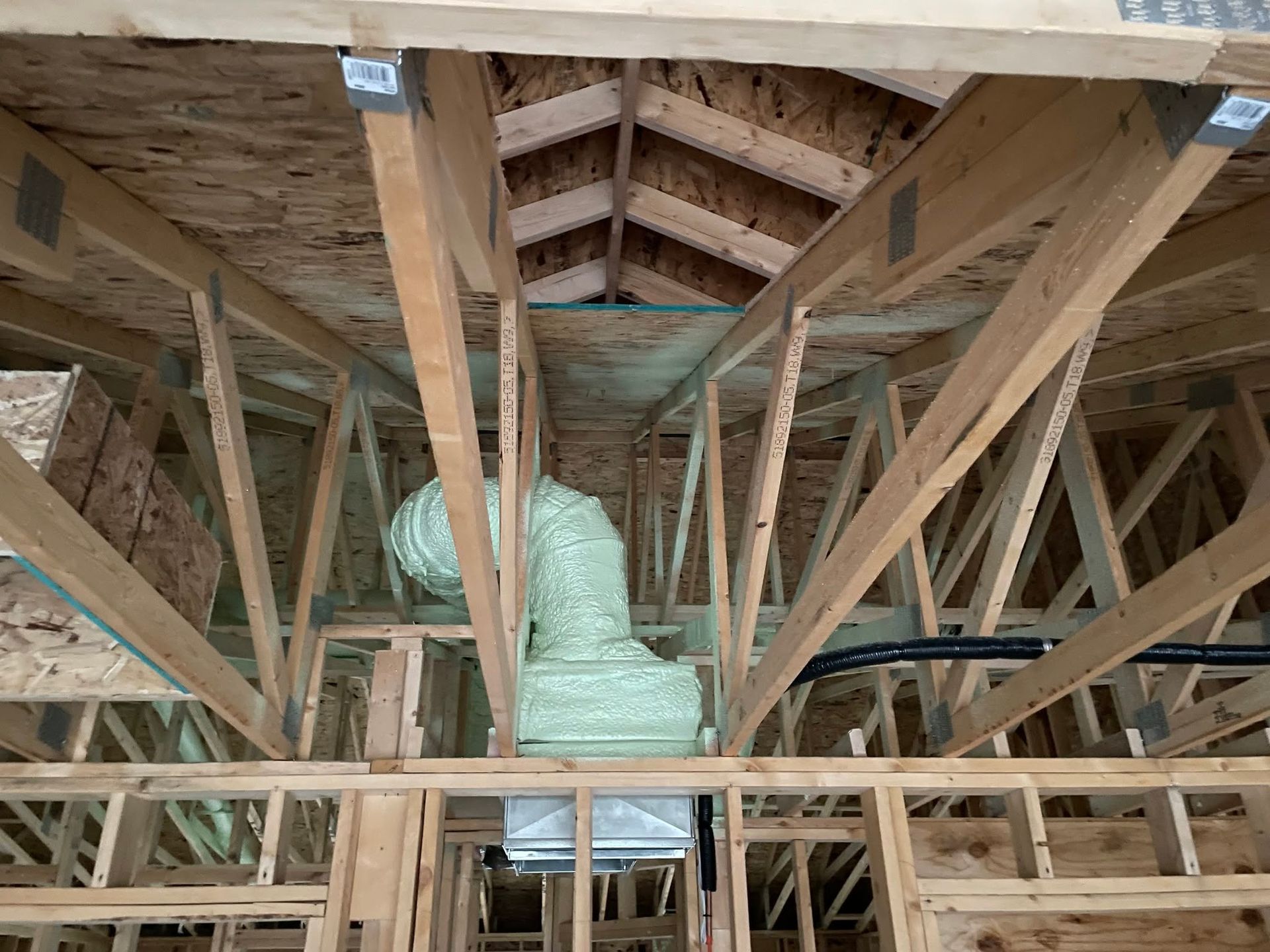 Attic with exposed wooden trusses and ductwork during construction